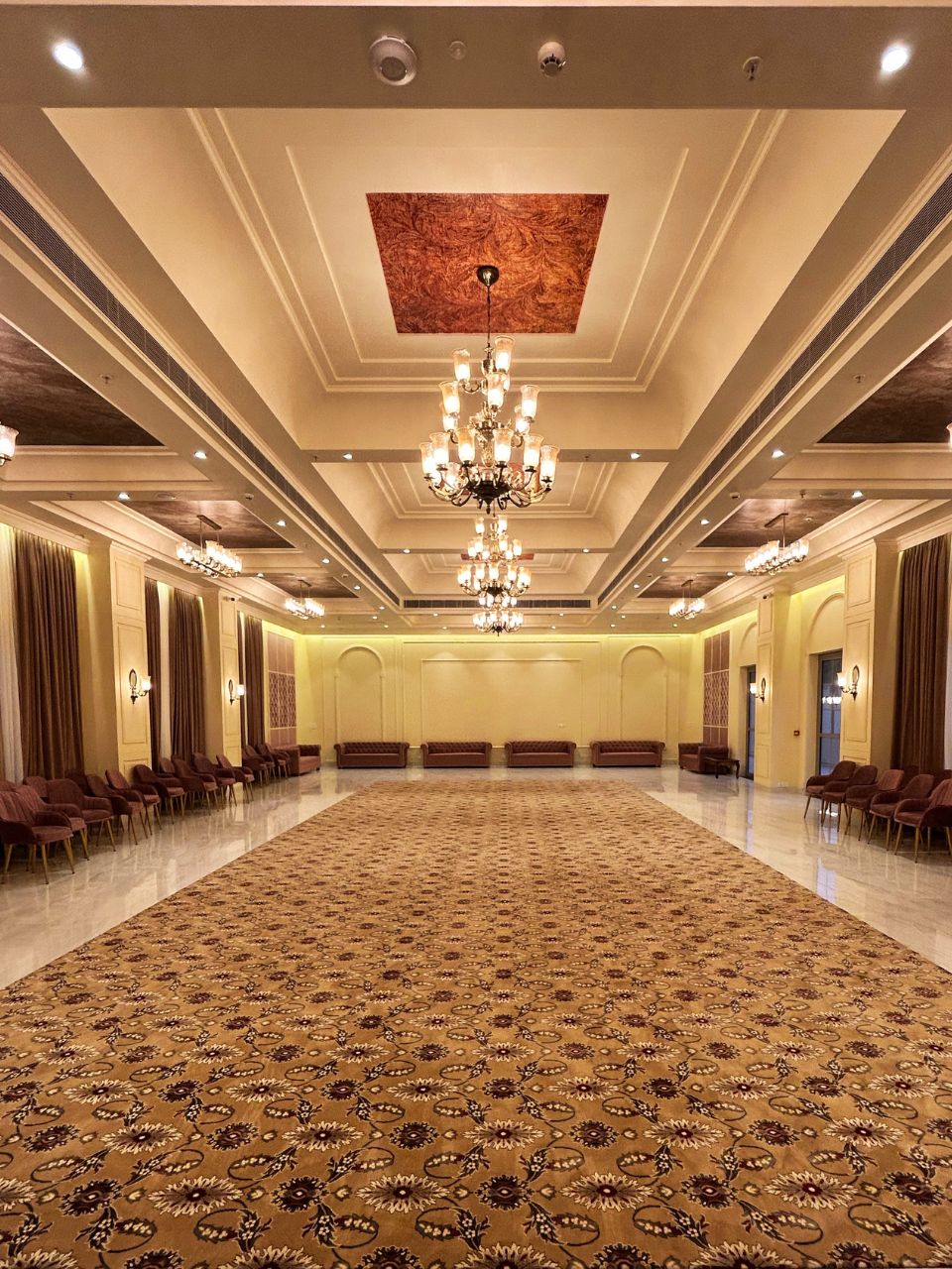 Banquet hall carpeted aisle with chandeliers at Vankamal Resort, Jaipur